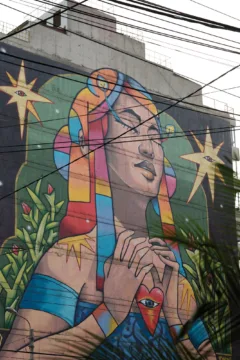 Street art in Lima. Shows a woman in colourful clothes, holding a heart.