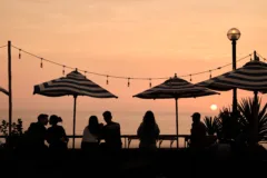 People sat under parasole silhouetted against setting sun