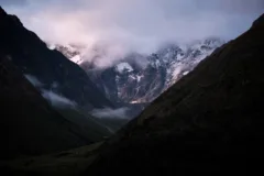 Views along a valley in Soray, Peru. There are snow capped mountains and clouds in the distance.