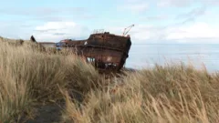 A rusty shipwreck on a grass bank on the coast of Tierra del Fuego, Chile.