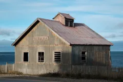 An abandoned wooden blacksmith on Estancia San Gregorio in Tierra del Fuego, Chile. The ocean can be seen behind the building.