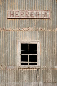 An old wooden sign reading "herrería" on the side of an old blacksmith in Tierra del Fuego, Chile.