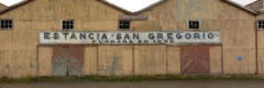 A large yellow sheep shearing shed, with a black and white sign reading "Estancia San Gregorio" in Tierra del Fuego, Chile.