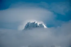 Snowy mountain peak emerging through clouds in Torres del Paine National Park, Chile.