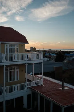 Views across the Chilean city of Punta Arenas, showing a tall yellow hotel with white balconies in the foreground.