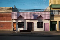 A small white house with a pink roof and door, in Punto Notales, Chile.