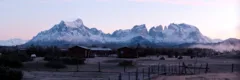 Cabins backed by snow-capped mountains in Torres del Paine, Chile. View is from the banks of the Serrano River.