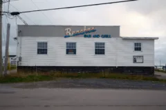 A white wooden building with a colourful sign reading Beaches Bar And Grill on the side.