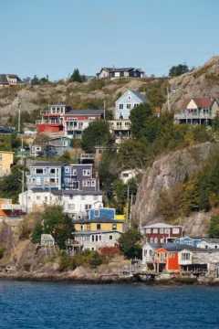 Colourful houses dotted on a hillside that leads to the ocean.