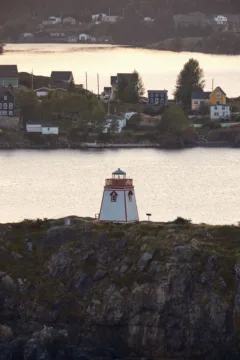 A white and red lighthouse standing on some rocks.