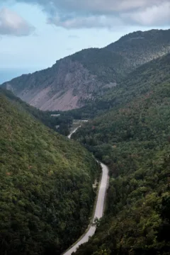 A long road winds through forest covered hills.