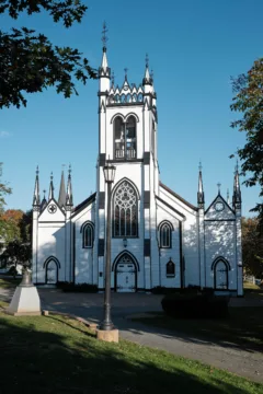 A large white church with stained glass windows and pointy, narrow spires.