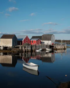 Small fishing boats are docked at a harbour with colourful wooden buildings.