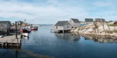 Wooden buildings on stilts sit in the ocean in a small fishing harbour.