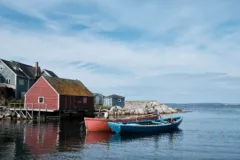 Small colourful fishing boats sit in the water in front of bright wooden buildings.