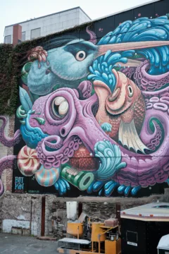 Street art on a wall shows colourful fish, octopus and birds.