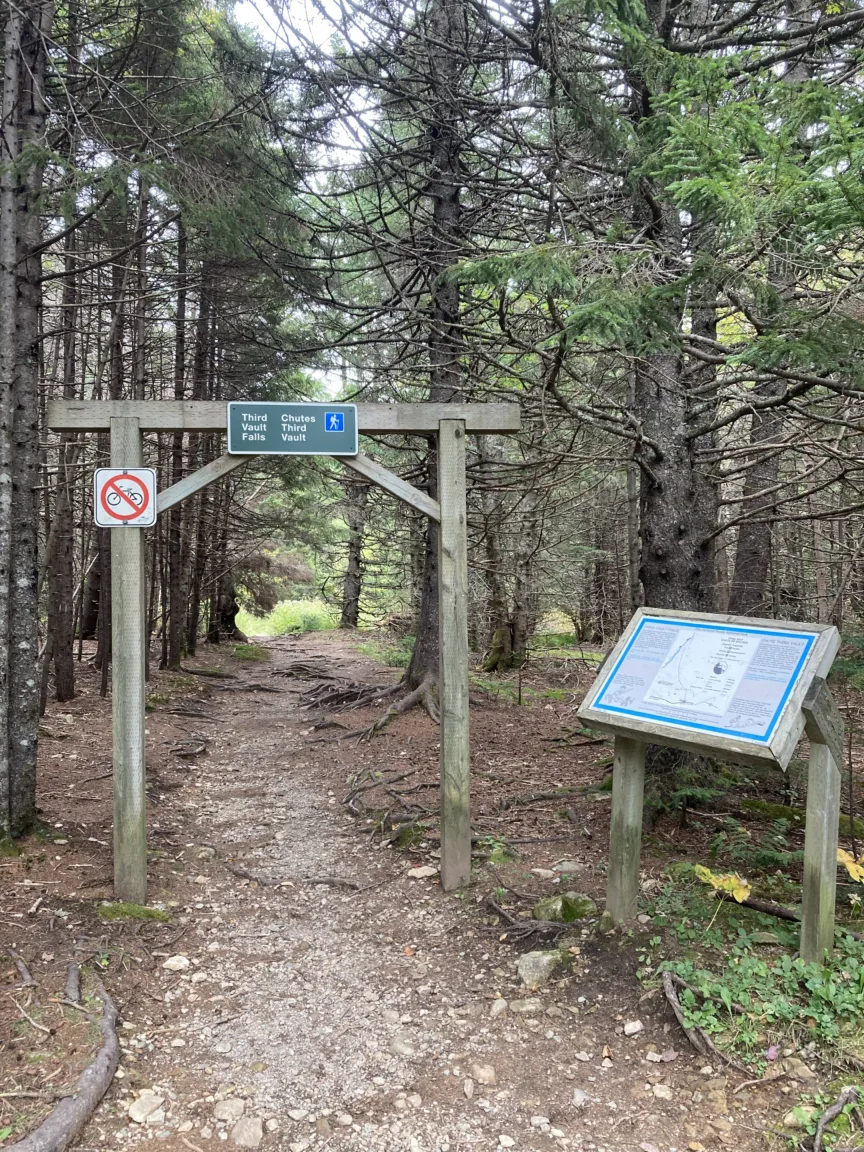 A gravel path leading into a wooded area. A sign reads Third Vault Trail.