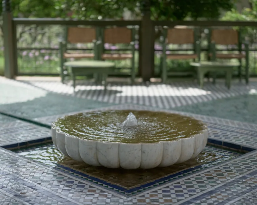 A small shallow fountain is surrounded by blue Moroccan floor tiles.