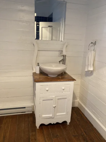 A white vintage sink is sat on a wooden bathroom cabinet. There is a mirror above it.