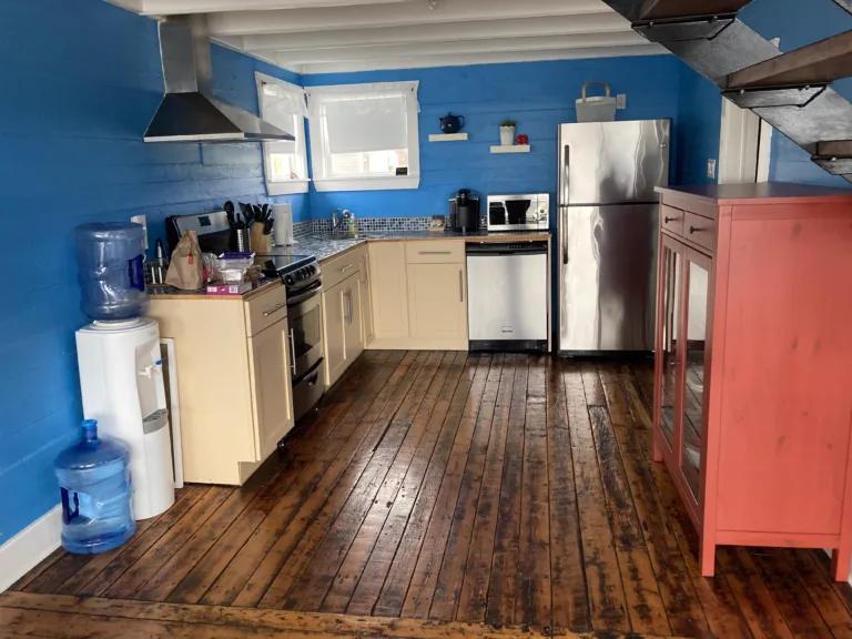 A modern kitchen with bright blue walls, cream cabinets and wooden floors.