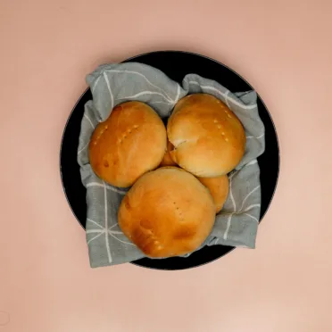 A black bowl full of freshly baked bread rolls.