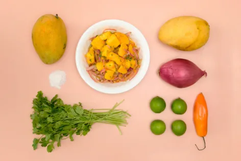 Overhead of ingredients for Mango Ceviche on a pink background.