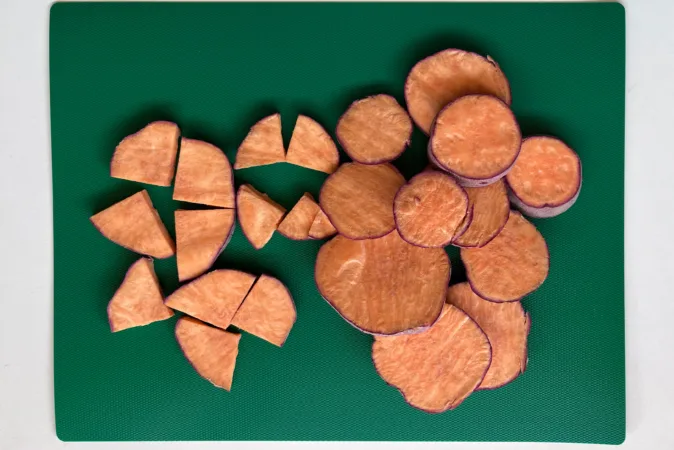 Slices of sweet potato on a green chopping board.