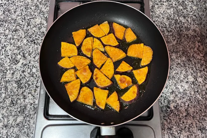 Fried sweet potato slices in a frying pan.