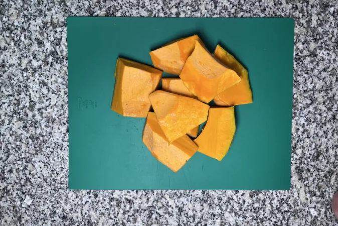 Large chunks of butternut squash on a green chopping board.