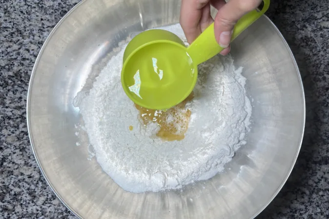 Water is being poured into a bowl, it is full of ingredients to make bread.