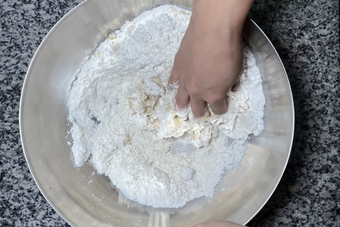 A hand mixing ingredients to make bread dough.