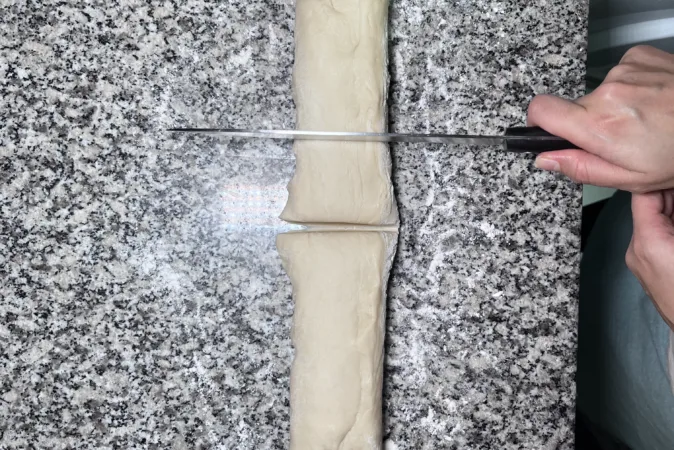 A length of dough being cut into portions.