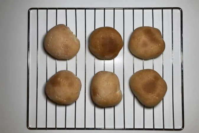 6 freshly baked chilean bread rolls (pan amasado) on a wire rack.