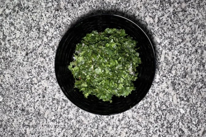 A black bowl full of chopped coriander.