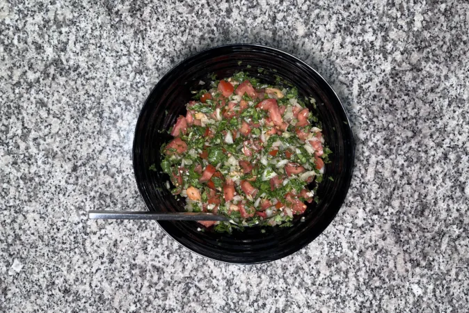 A black bowl full of pebre, a fresh Chilean salsa.