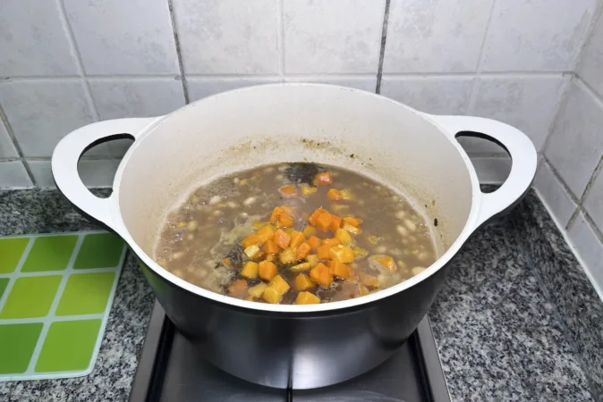 A bean and squash stew simmering in a large soup pan.