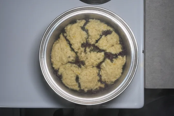 A metal saucepan with blueberry grunt inside.