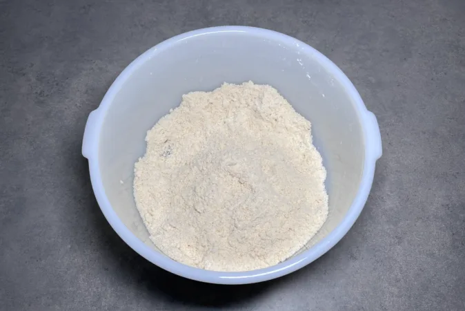 A white mixing bowl with flour inside.