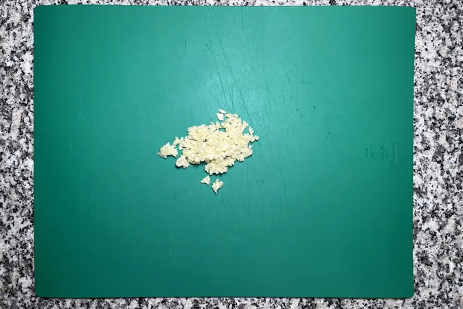 Minced garlic on a green chopping board.