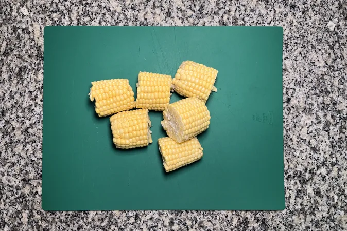 Chunks of corn on the cob, placed on a green chopping board.