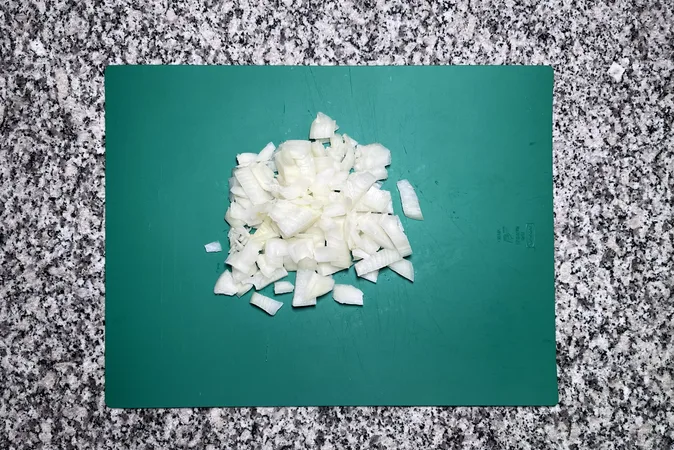 A chopped onion on a green chopping board.