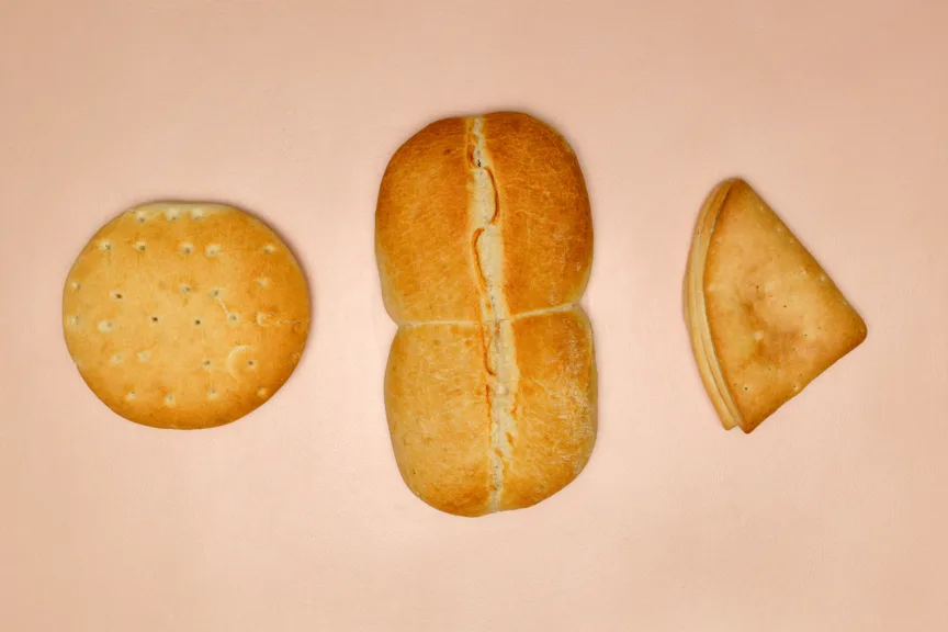 Three types of traditional Chilean bread (hallulla, marraqueta and dobladitas)  on a pink background.